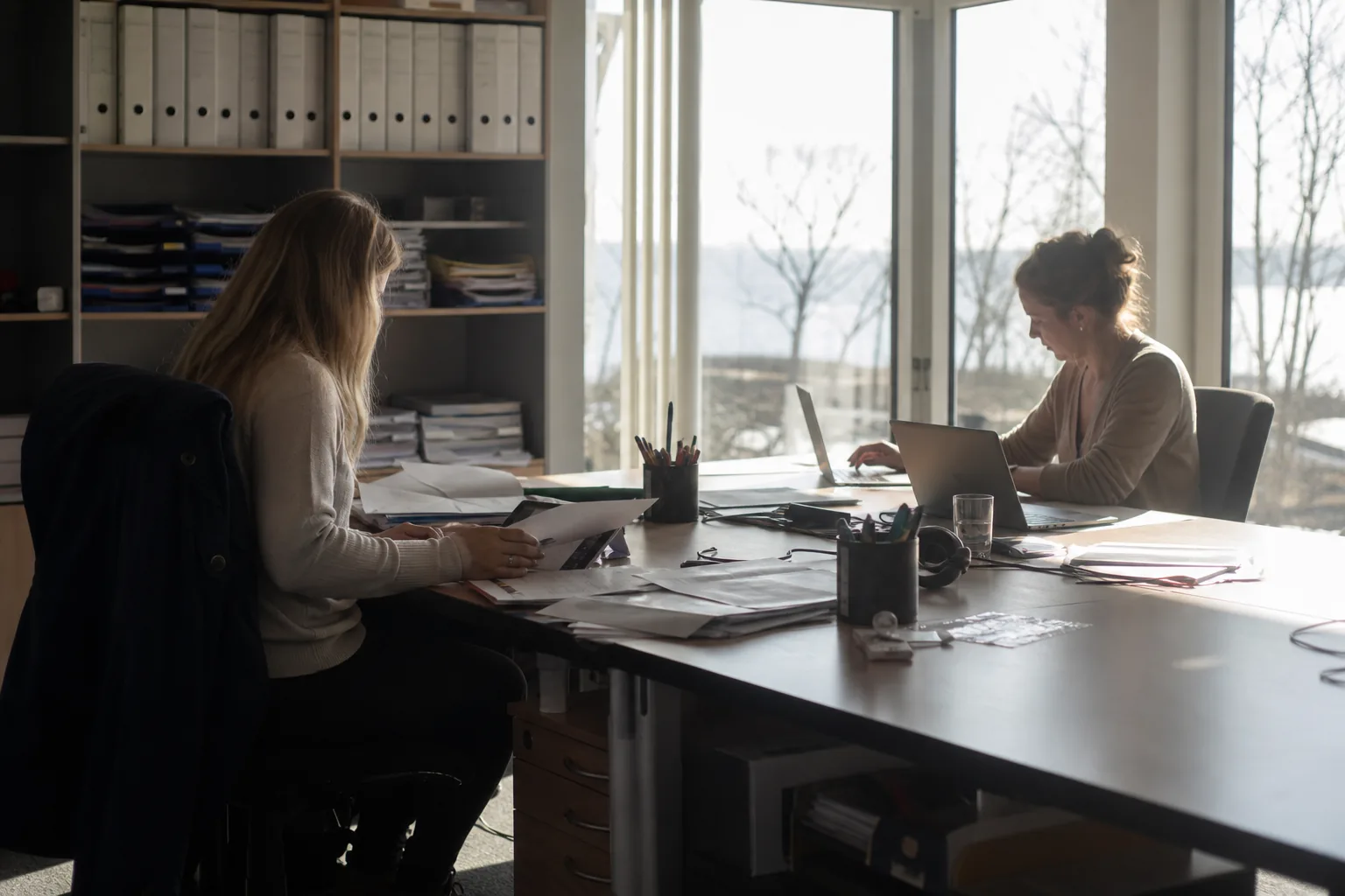 Papierlisten, Tabellenkalkulation und digitale Gästeliste liegen nebeneinander auf einem Schreibtisch