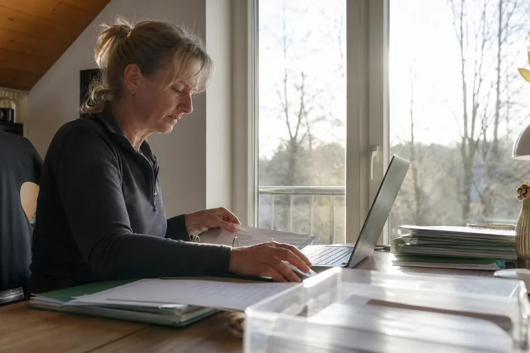 Ordner, Laptop mit Gästeliste und sortierte Belege auf einem Schreibtisch